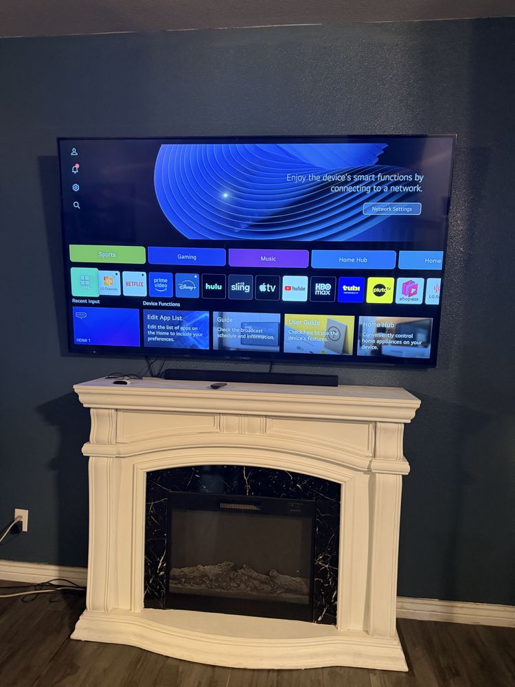 A TV mounted above a white fireplace mantel